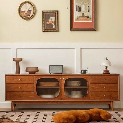 a dog laying on the floor in front of a dresser with two pictures above it