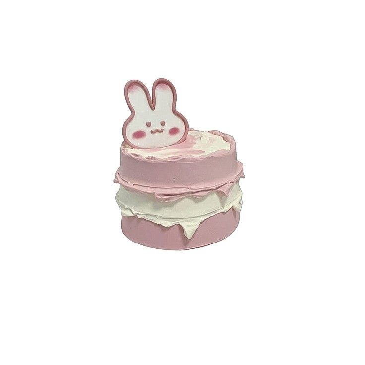 a pink cake with white frosting and a bunny decoration on top, sitting in front of a white background