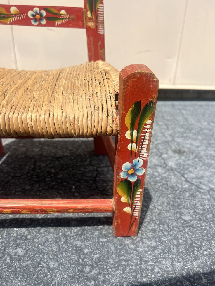 an old wooden chair with a flower painted on it's seat and backrest