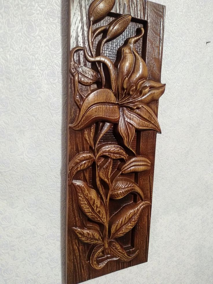 a wooden plaque with flowers and leaves carved into it's sides on a wall