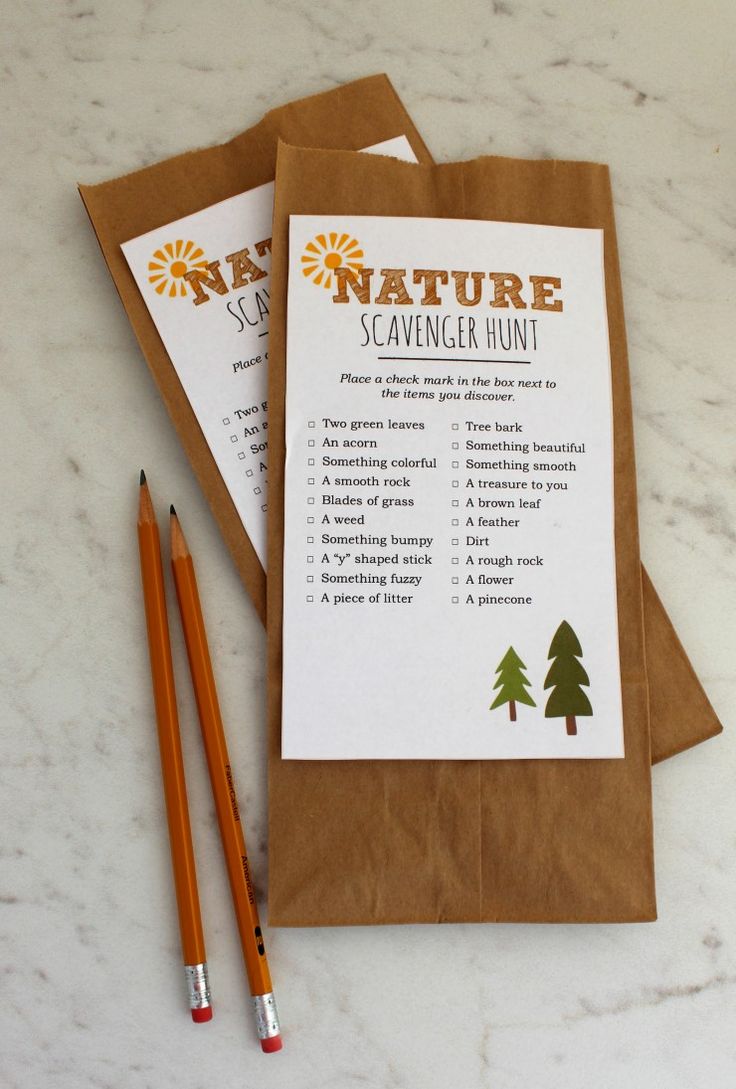 two brown paper bags sitting on top of a table next to pencils and markers