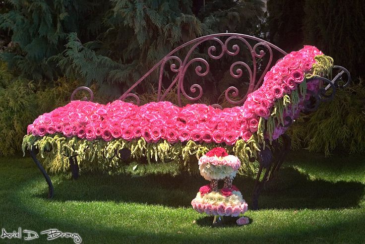 a pink bench with flowers on it in the grass