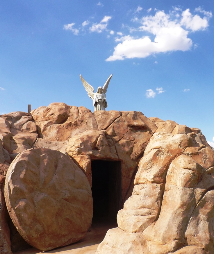 there is a statue on top of a rock with a bird flying over it in the sky