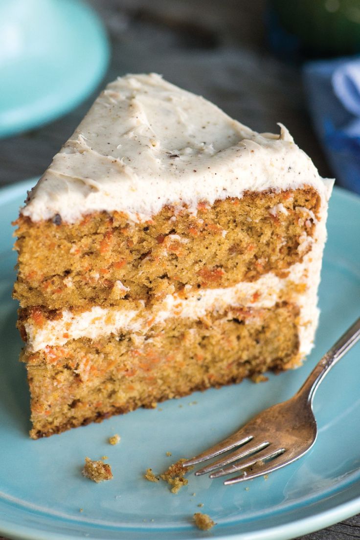 a piece of carrot cake on a blue plate with a fork and napkin next to it