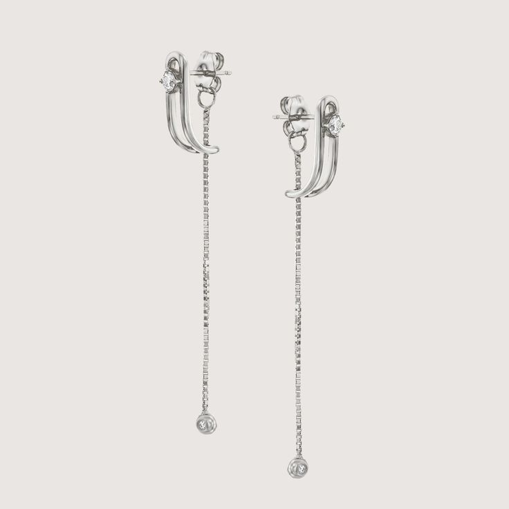 An impressive and special earring with a design element in the form of a vertical clasp inspired by the world of tailoring that characterizes the TAILORED collection. The top of the element is studded with a 3 mm diamond that gives the earring a powerful look without detracting from its delicacy. A delicate chain with a diamond-studded gold ball at the end, threaded from the bottom of the earring, adds an elegant sway to this special piece. The earring is inspired by the buttons and cuffs that make up the female suit and is part of the TAILORED collection The earrings are sold as singles All features can be customized! Please contact us if you wish to make changes, we love making custom designs. All of our jewelry is carefully handmade in our atelier. *HC diamond are all conflict-free diam Luxury Silver Clip-on Earrings For Formal Occasions, Classic Diamond Clip-on Earrings With Brilliant Cut, Classic Clip-on Diamond Earrings, Timeless Platinum Drop Earrings, Elegant Diamond White Clip-on Jewelry, Elegant Diamond Clip-on Earrings For Wedding, Luxury White Gold Clip-on Diamond Earrings, Elegant Platinum Diamond Earrings Gift, Elegant Diamond White Earrings With Diamond Accents