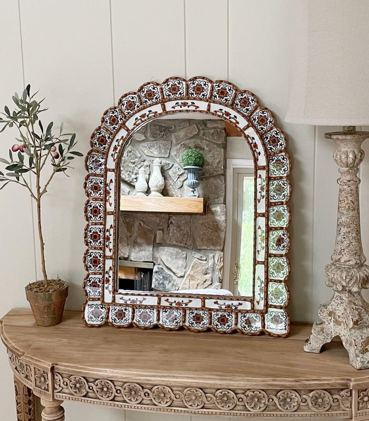 a mirror sitting on top of a wooden table next to a lamp and potted plant