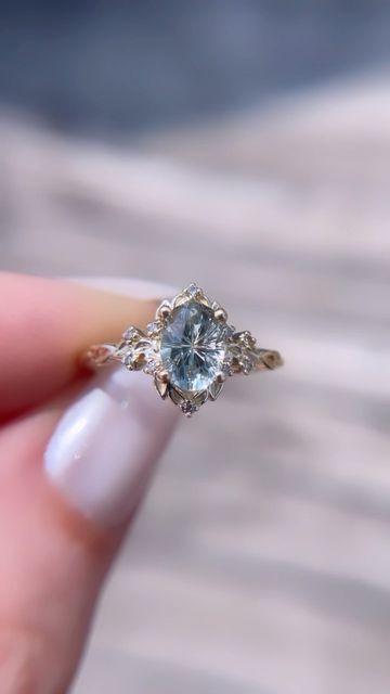 a woman's hand holding an engagement ring with a blue topazte stone