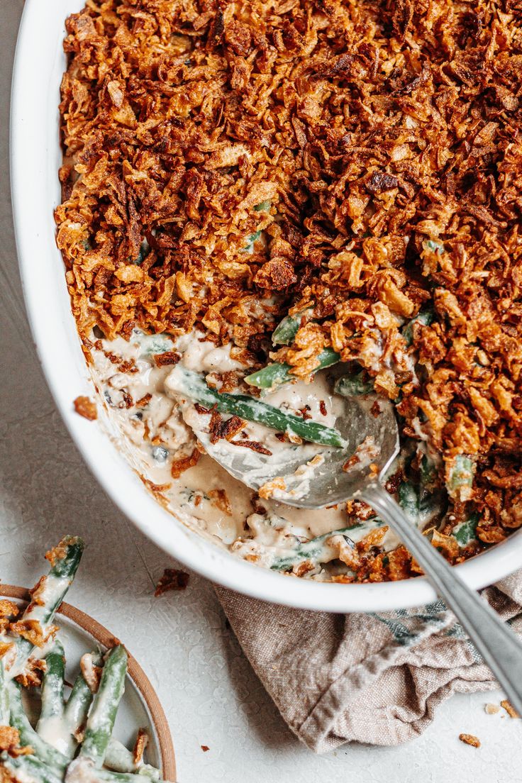 a white bowl filled with green bean casserole and topped with whipped cream sauce