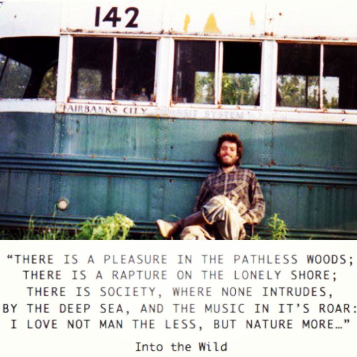 a man sitting on the side of a bus in front of some weeds and trees