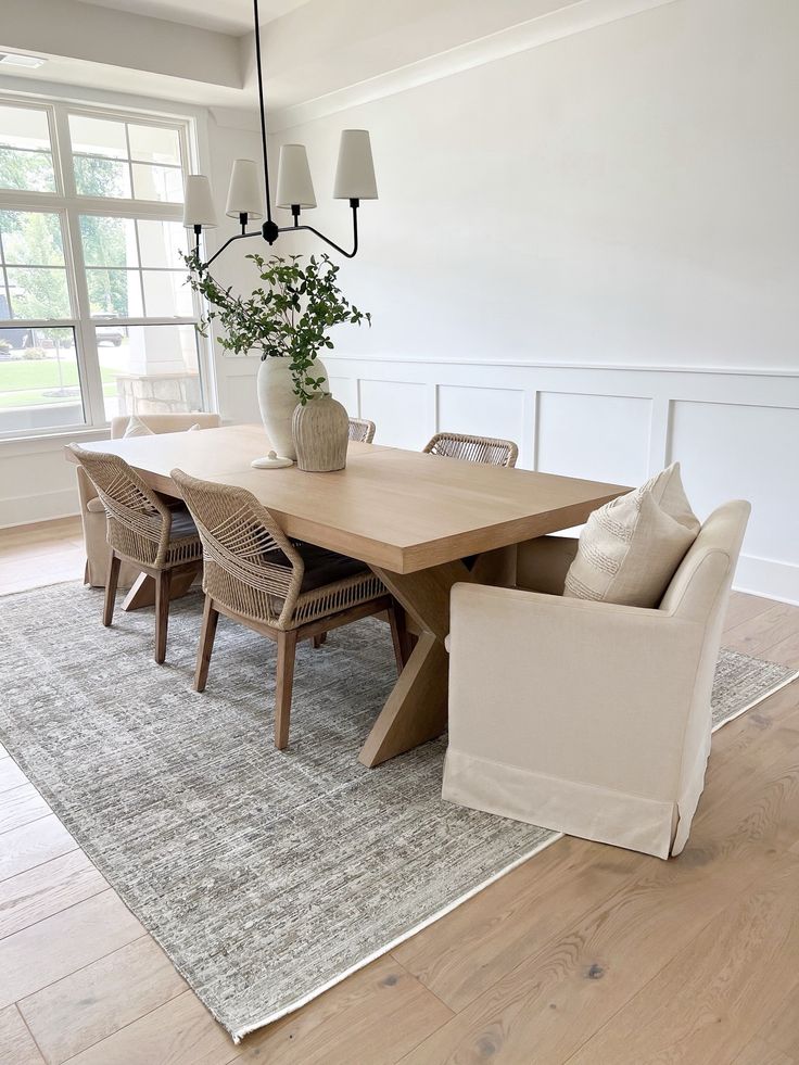 a dining room table with chairs and a rug on the floor in front of it