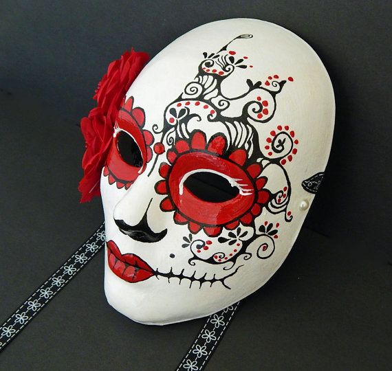 a white mask with red flowers painted on it