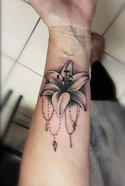 a woman's wrist with a flower and beads tattoo design on it, in black and white