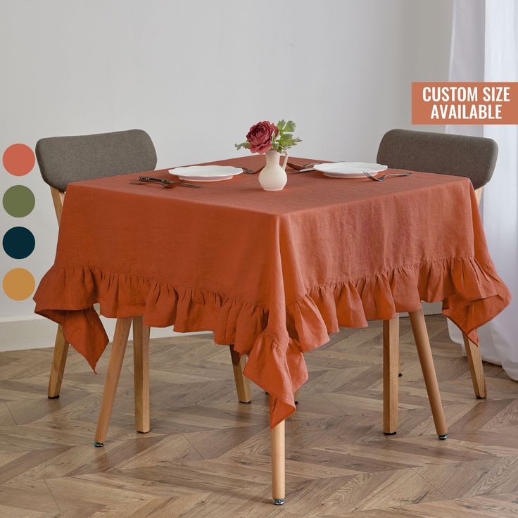 an orange table cloth with ruffled edges sits on top of two wooden chairs in front of a white wall