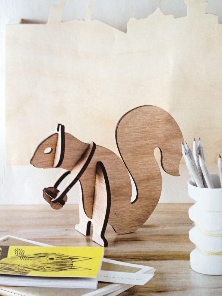 a wooden toy squirrel sitting on top of a table next to pencils and markers