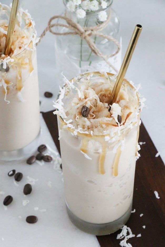 two glasses filled with drinks sitting on top of a wooden table next to chocolate chips