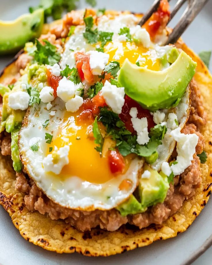 an egg and avocado on top of tortilla