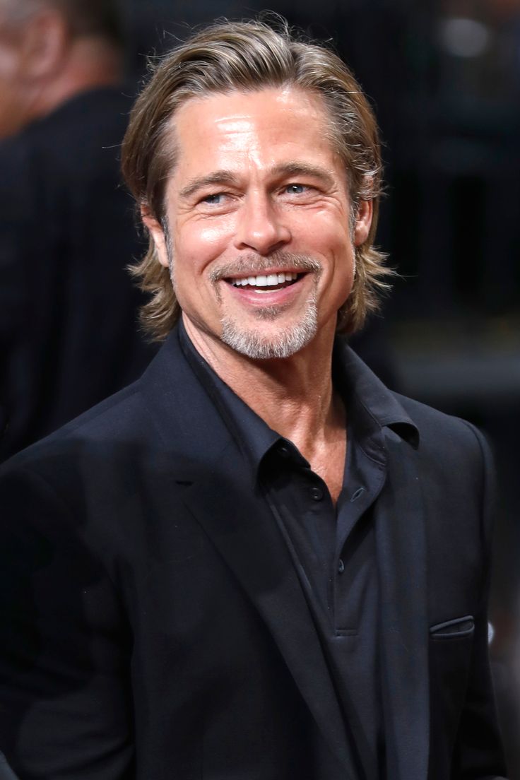 the actor is smiling and wearing a black suit