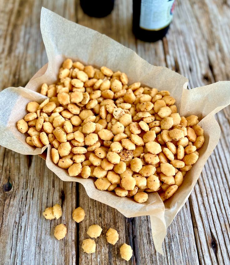 a bunch of peanuts sitting on top of a wooden table next to a bottle of wine