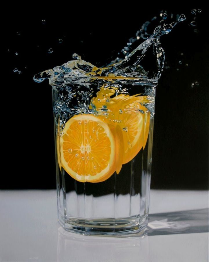 an orange slice being dropped into a glass of water with splashes on the side