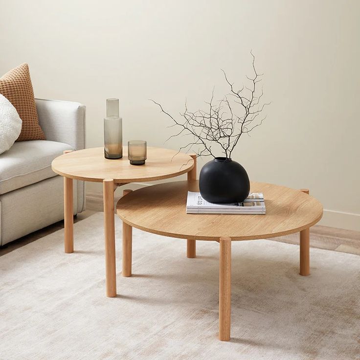 two coffee tables sitting on top of a rug in a living room next to a couch