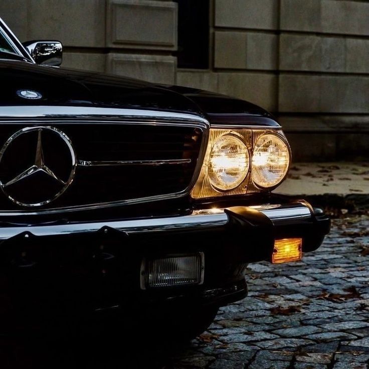 the front end of a black mercedes benz coupe parked on a cobblestone street