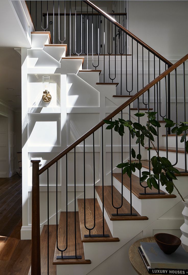 there is a plant that is growing on the stair railing in this house with white walls and wood flooring