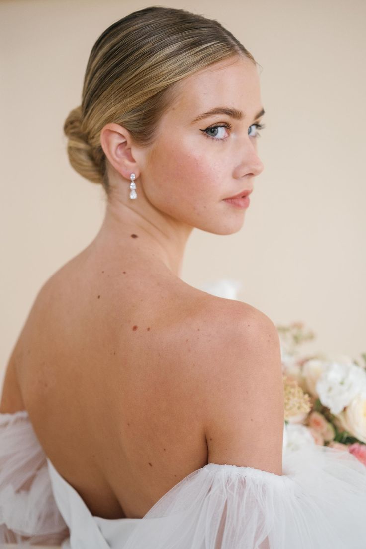 a woman wearing a white dress and earrings