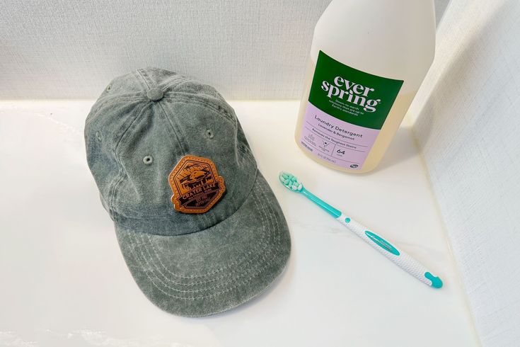 a hat, toothbrush and bottle of mouthwash sitting on a counter next to it