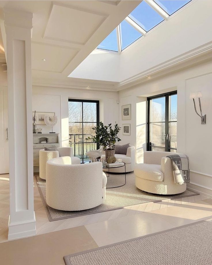 a living room filled with white furniture and lots of windows on top of the ceiling