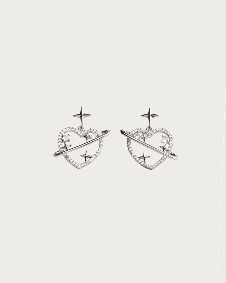 Introducing our Celestial Earrings, an exquisite addition to any outfit. Inspired by the stars and moon, these earrings feature delicate and intricate details that elevate your look to the heavens. Crafted with care and designed to complement your unique style, these earrings are a must-have for any fashion-forward individual. Materials: platinum plated brass, cubic zirconia Measurements: 16mm/0.6" in saturn length Nickel Free Celestial Earrings, Trendy Sterling Silver Earrings For Wedding, Trendy Sterling Silver Wedding Earrings, Dainty Silver Pierced Crystal Earrings, Silver Celestial Crystal Earrings As Gift, Celestial Style Pierced Earrings For Wedding, Celestial Style Earrings As Gift, Pierced Metal Star Earrings, Sterling Silver Star Earrings For Wedding