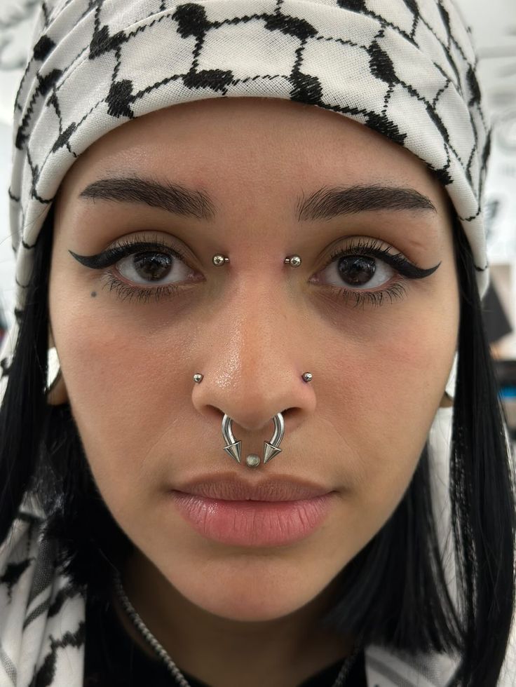 a close up of a person with piercings on their nose and nose ring in front of her face