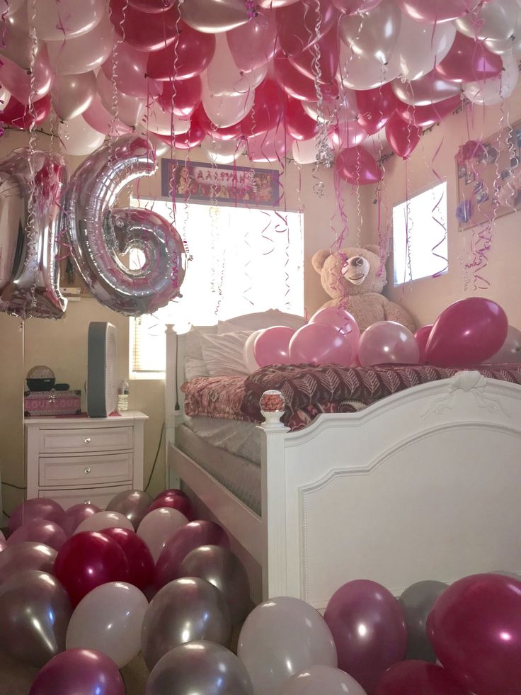 a room filled with lots of balloons and a teddy bear on top of the bed