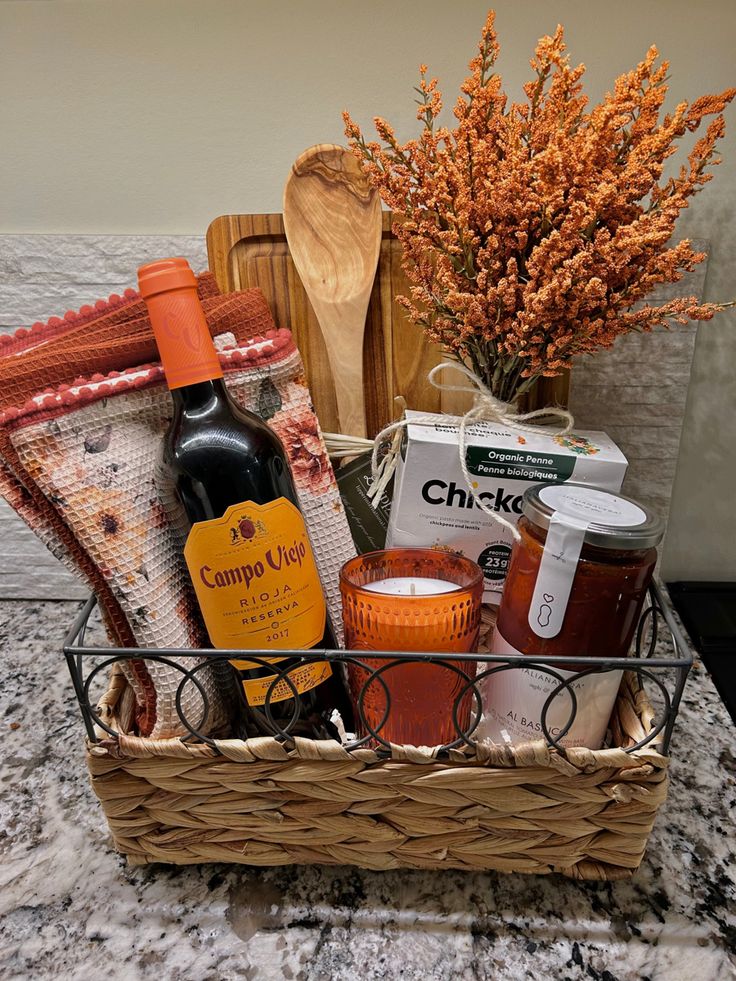 Fall themed gift basket with orange and wood accents. Gift basket is pasta date-night themed and includes red Italian wine, gluten free chickpea pasta, pasta sauce, candle, kitchen towel, wooden spoon and orange accents. Accents are decorative floral and tweed. Pasta Night Gift Basket, Wine And Pasta Gift Basket Ideas, Pasta Making Gift Basket, Date Night Hamper, Pasta Themed Gift Basket, Kitchen Basket Gift Ideas, Date Night In Basket, Charcuterie Basket Ideas, Italian Basket Gift Ideas