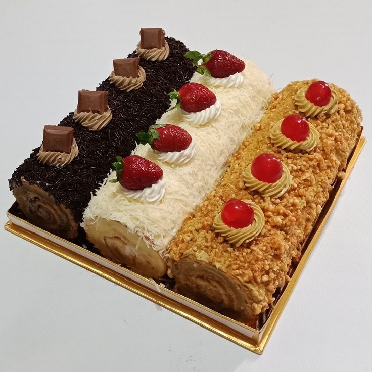 three layered cake with strawberries, chocolate and cherries on each layer in a gold tray