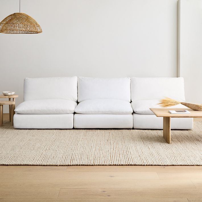 a white couch sitting on top of a wooden floor next to a table and lamp