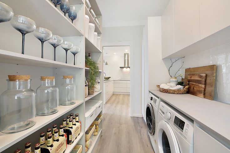 a washer and dryer in a room with white shelves filled with wine glasses