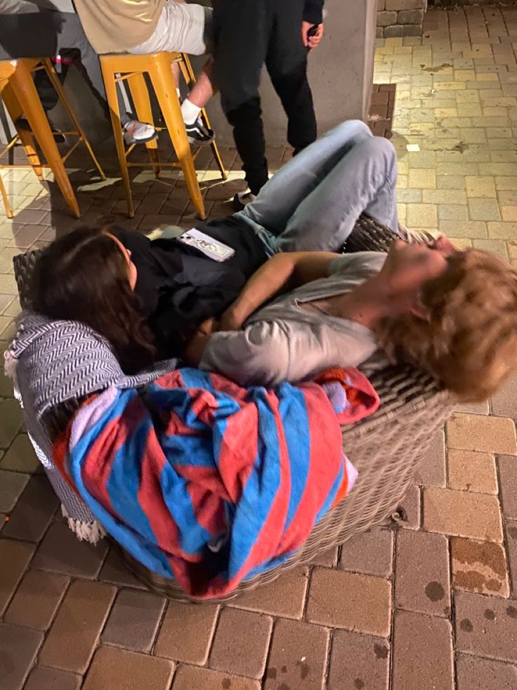 two people are laying on a hammock in the middle of a brick floor