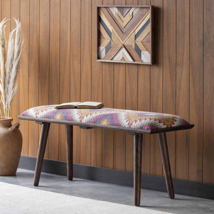 a bench and vase in front of a wooden wall