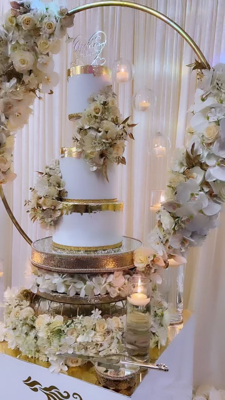 a three tiered cake with flowers and candles around it on top of a table