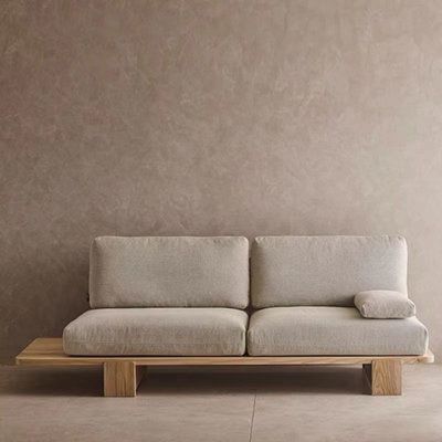 a white couch sitting on top of a wooden table in front of a gray wall