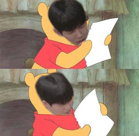 a boy is sitting down and reading a paper with winnie the pooh on it