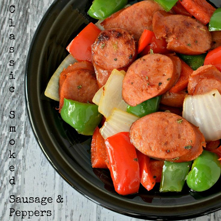 sausage and peppers in a black bowl on a white wooden table with text overlay