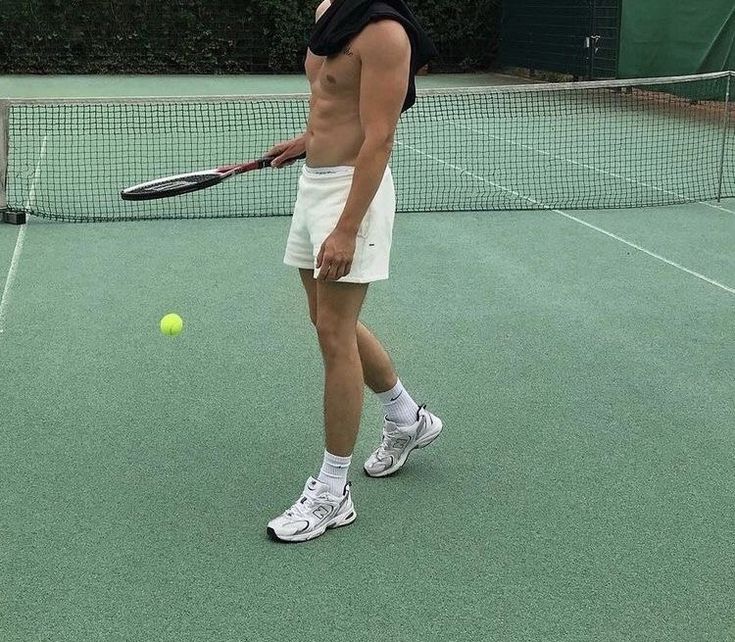 a man standing on a tennis court holding a racquet and ball in his hand