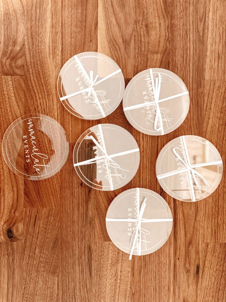 four clear coasters sitting on top of a wooden table