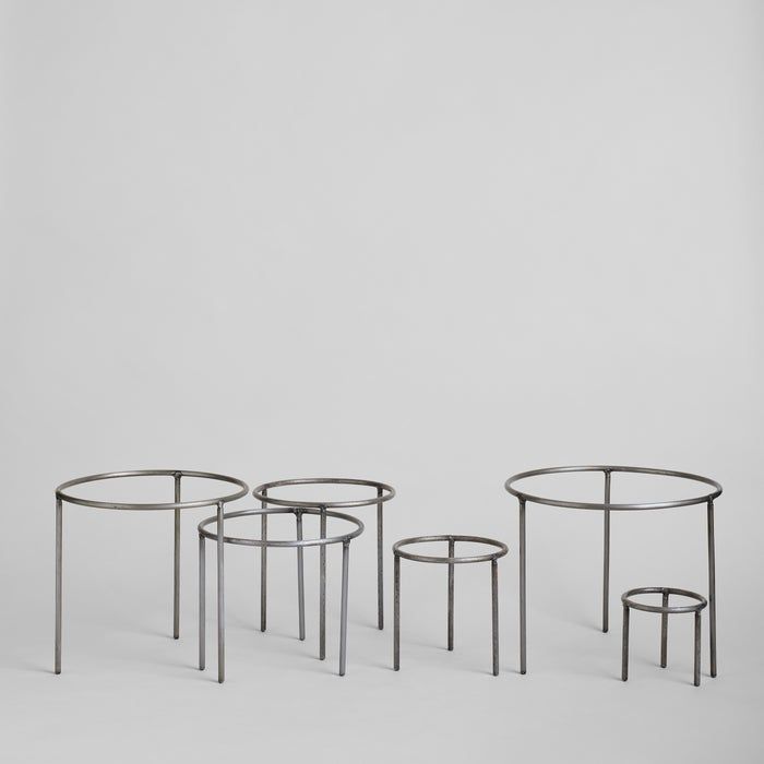 three metal tables sitting next to each other on a white surface with no one around them