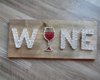 a wooden sign with the word wine spelled out in white lace and a glass of red wine