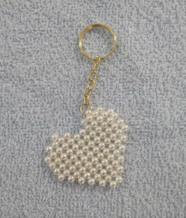 a keychain made out of pearls on a gray surface with a gold chain