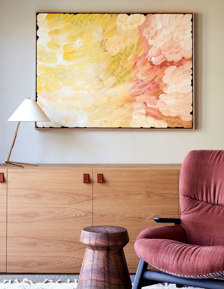 a painting hanging on the wall next to a chair and footstool in front of it