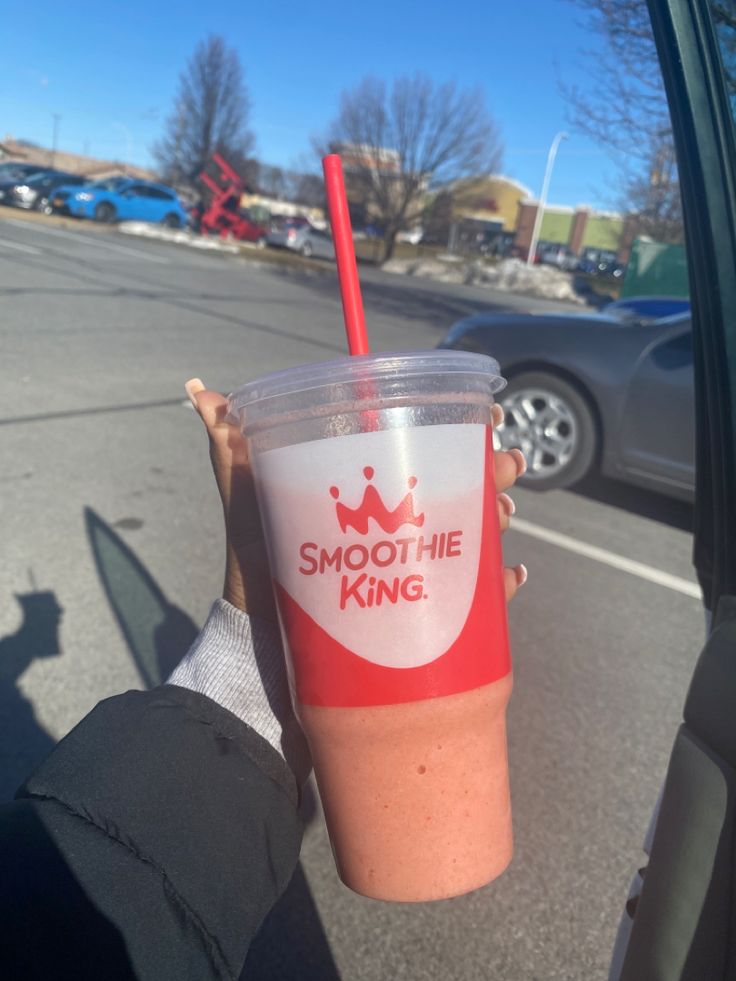 a person holding up a smoothie with a straw in their hand and the words smoothie king on it