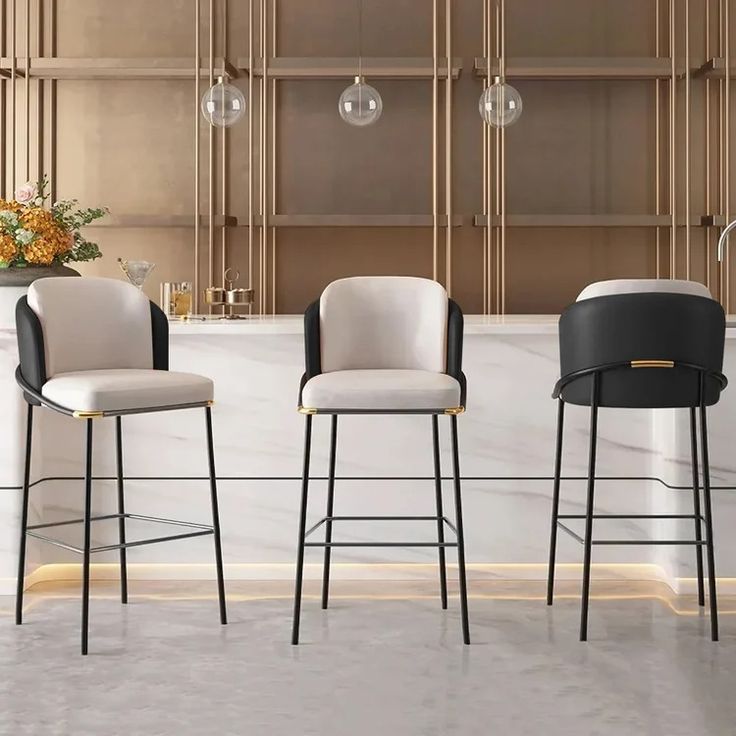 three modern bar stools with black and white upholstered seats in front of a marble counter